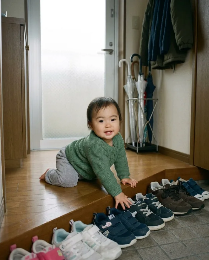 A baby crawling to the shoes lined up in the entryway